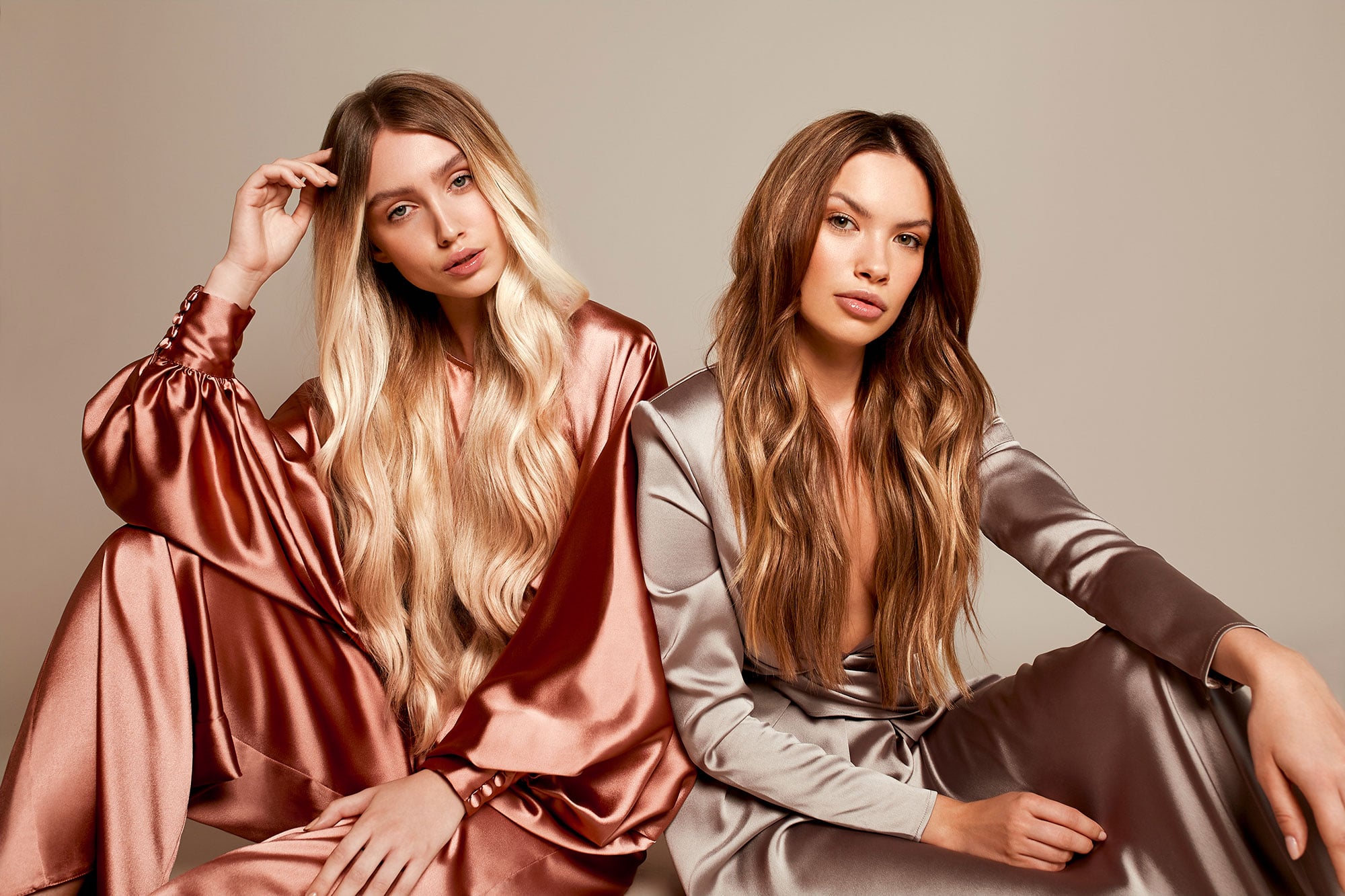 A blonde and brunette woman are sitting on the floor.