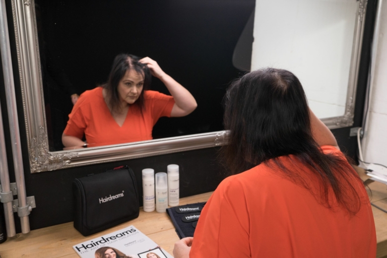 Woman looks at her scalp in the mirror
